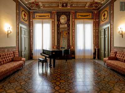 ...arricchito da un pianoforte a coda e una splendida specchiera alta quanto la parete